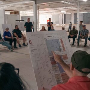older man showing building plans to a group of people
